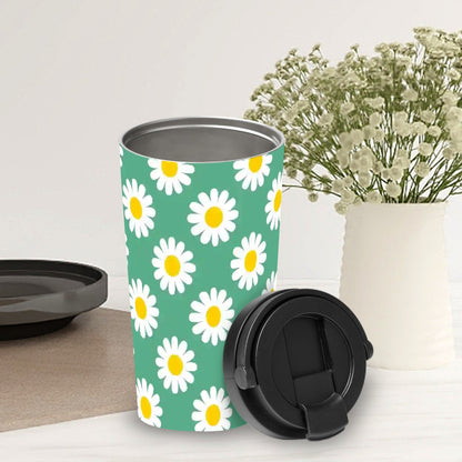 Green travel mug with white daisy pattern on a white surface with a vase of flowers in the background.