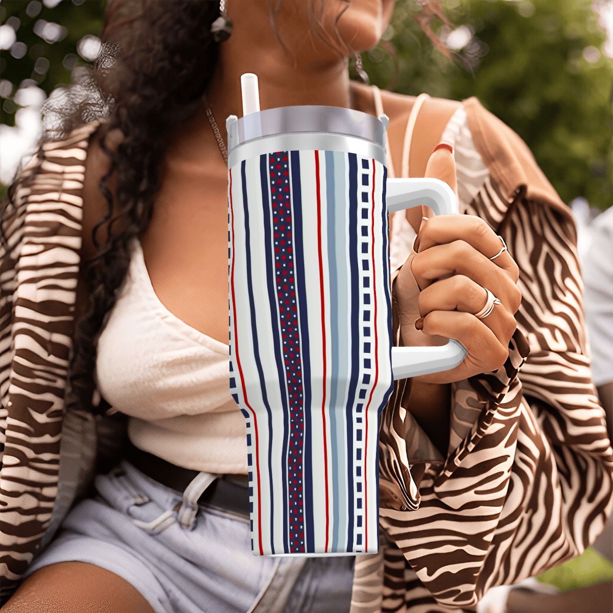 Person holding a striped mug outdoors