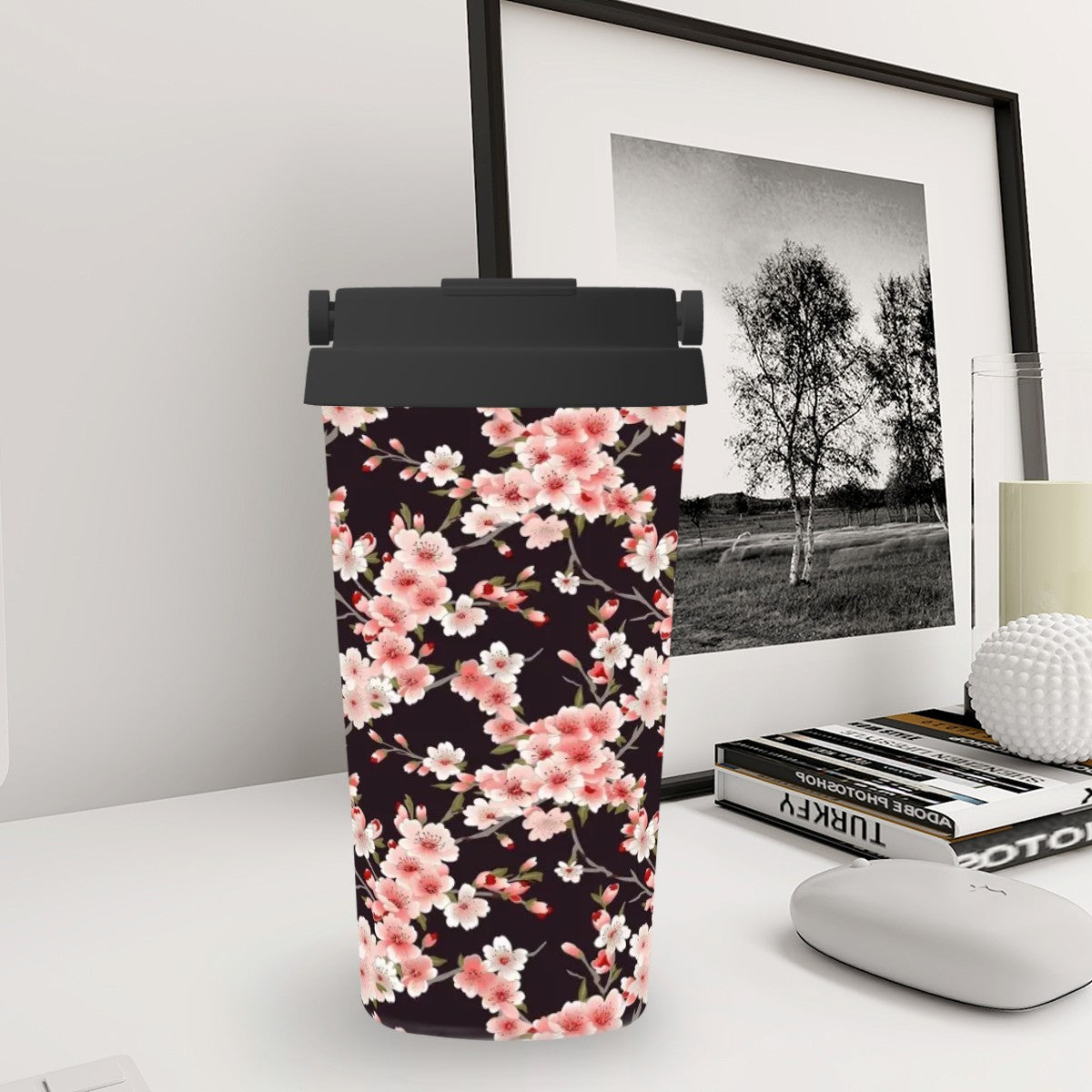 Tumbler with floral design on a desk next to a framed picture