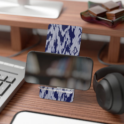 Phone stand with blue camouflage pattern on a desk with keyboard, mouse, and headphones.