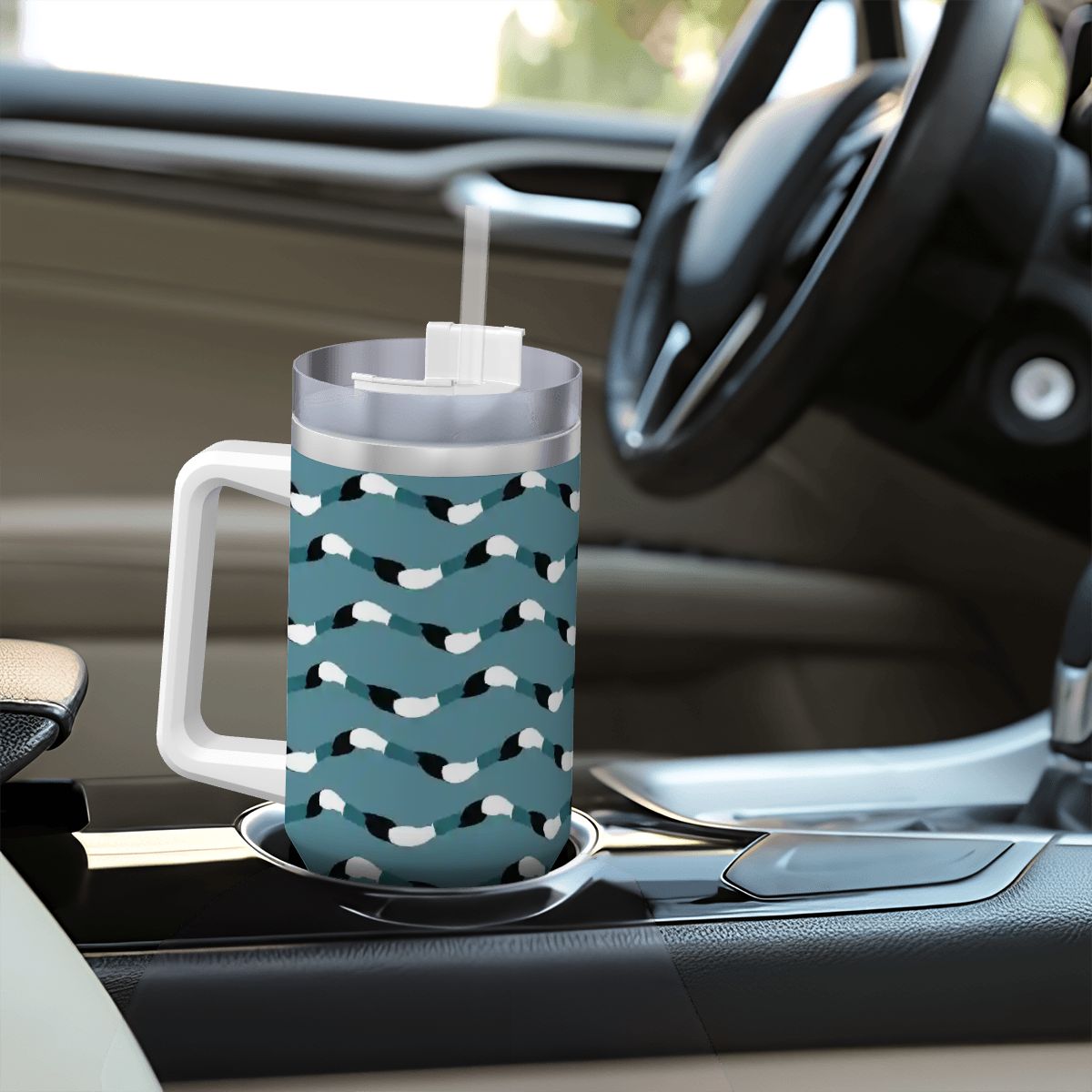 Blue patterned mug with a straw on a car cup holder
