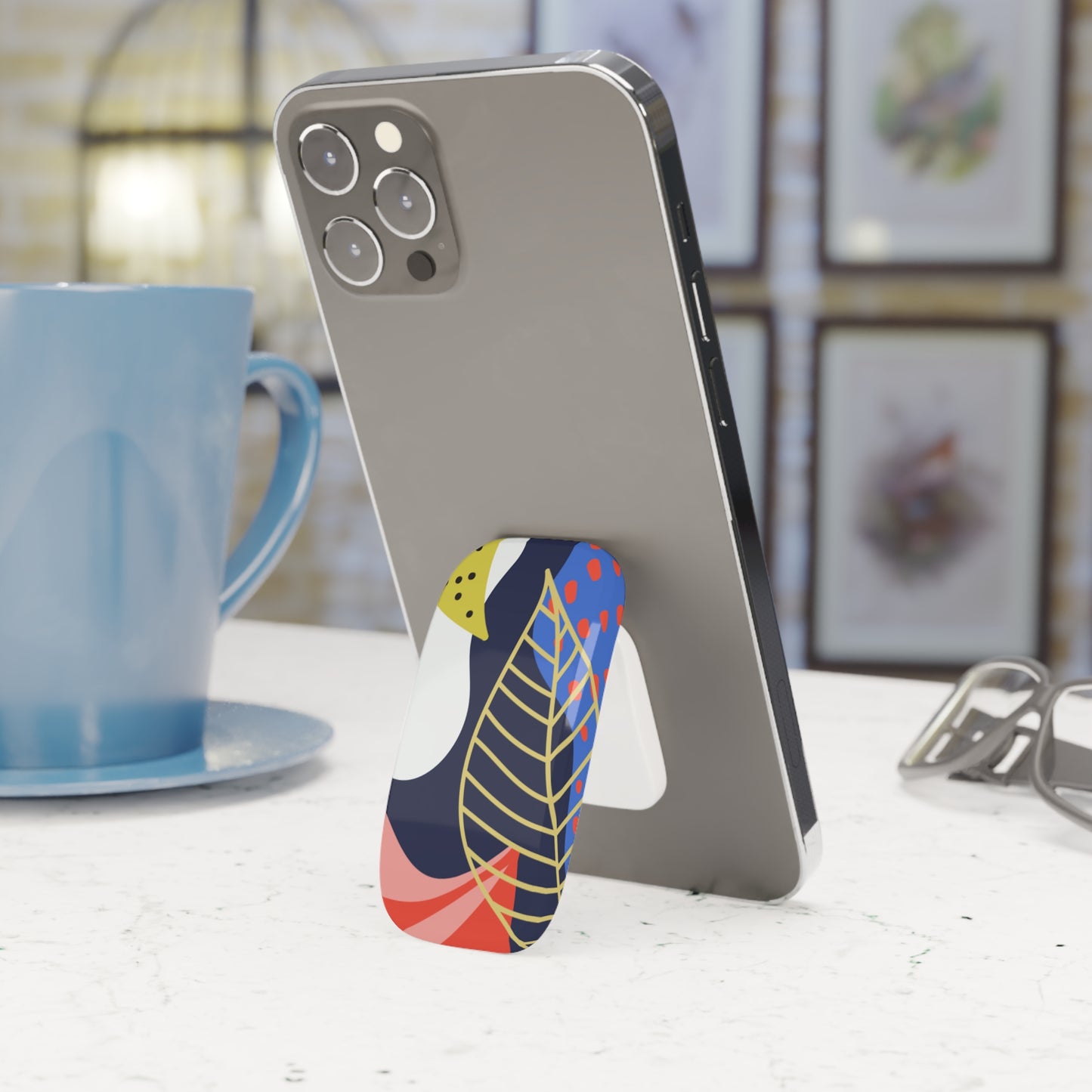 Phone case with colorful design on a desk next to a blue mug