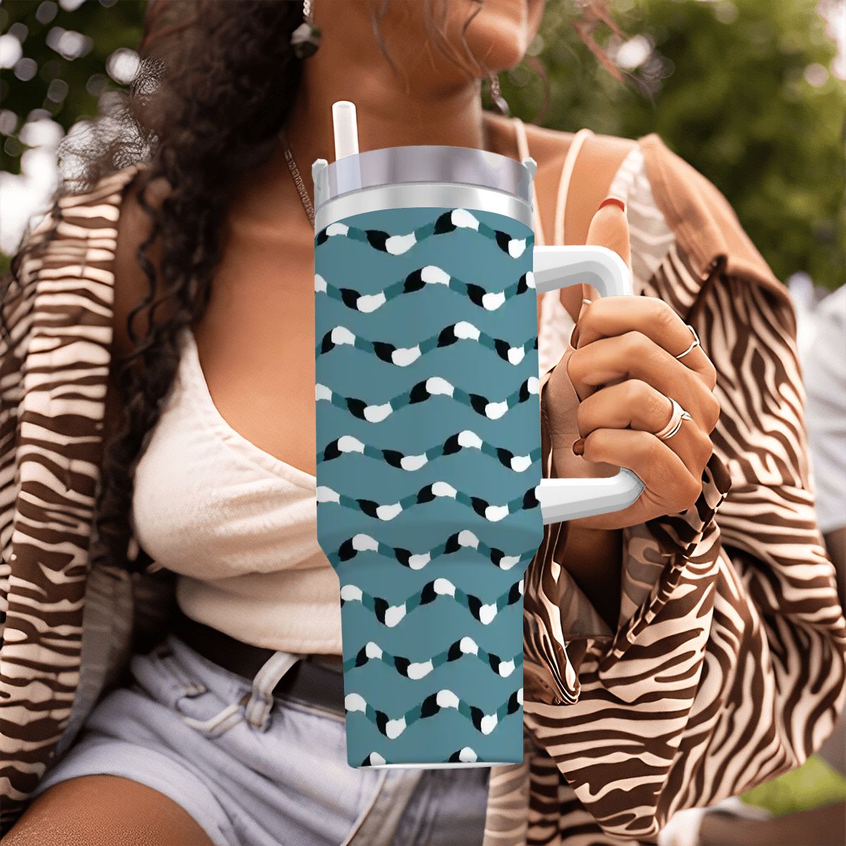 Person holding a blue water bottle with white patterns outdoors