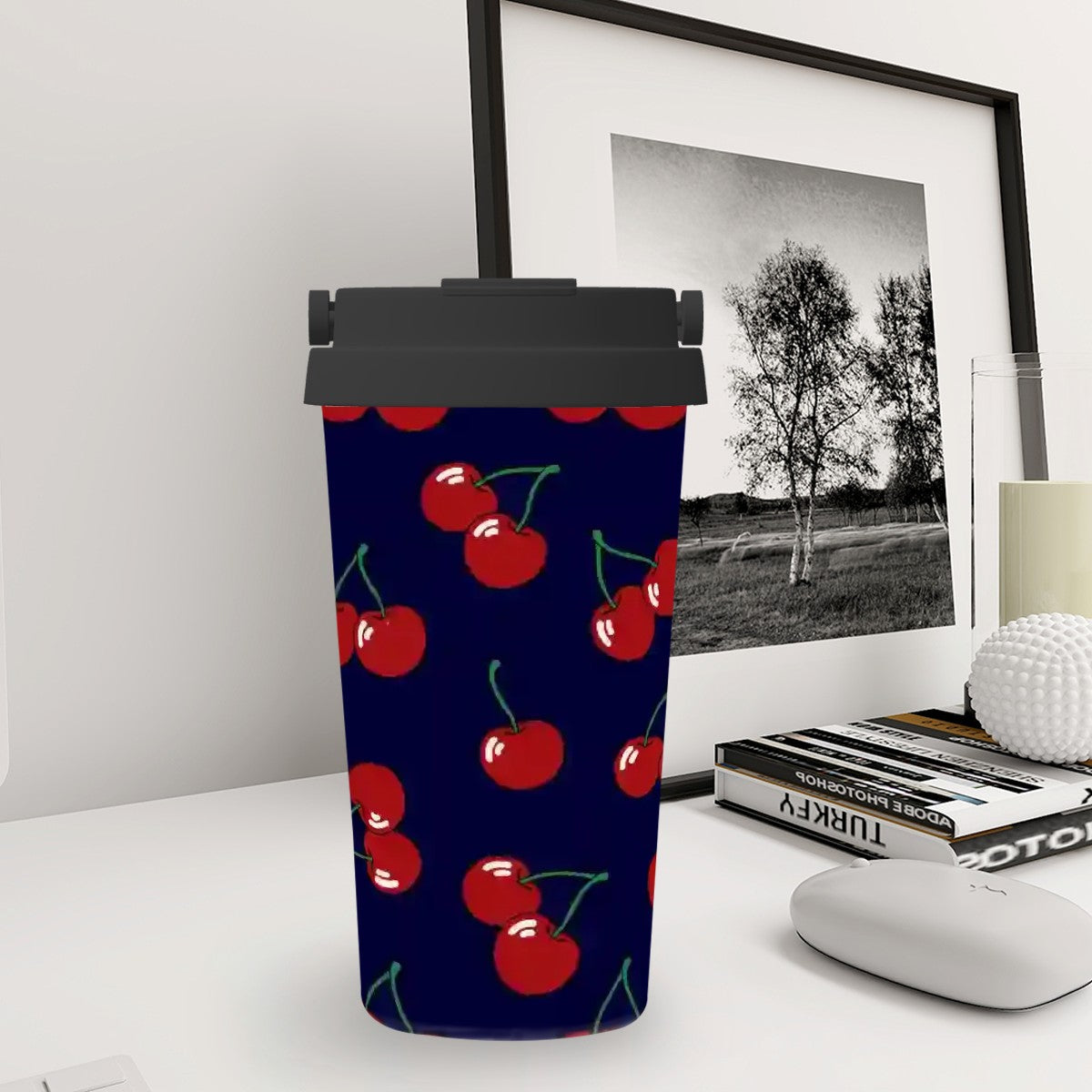 Tumbler with cherry pattern on a desk with books and a photo frame in the background