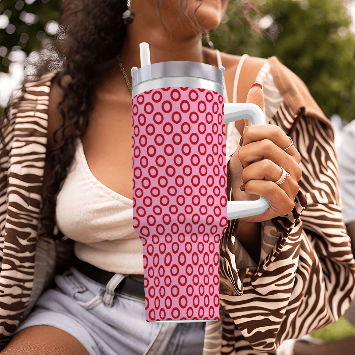 Person holding a pink polka dot water bottle with a zebra print jacket.