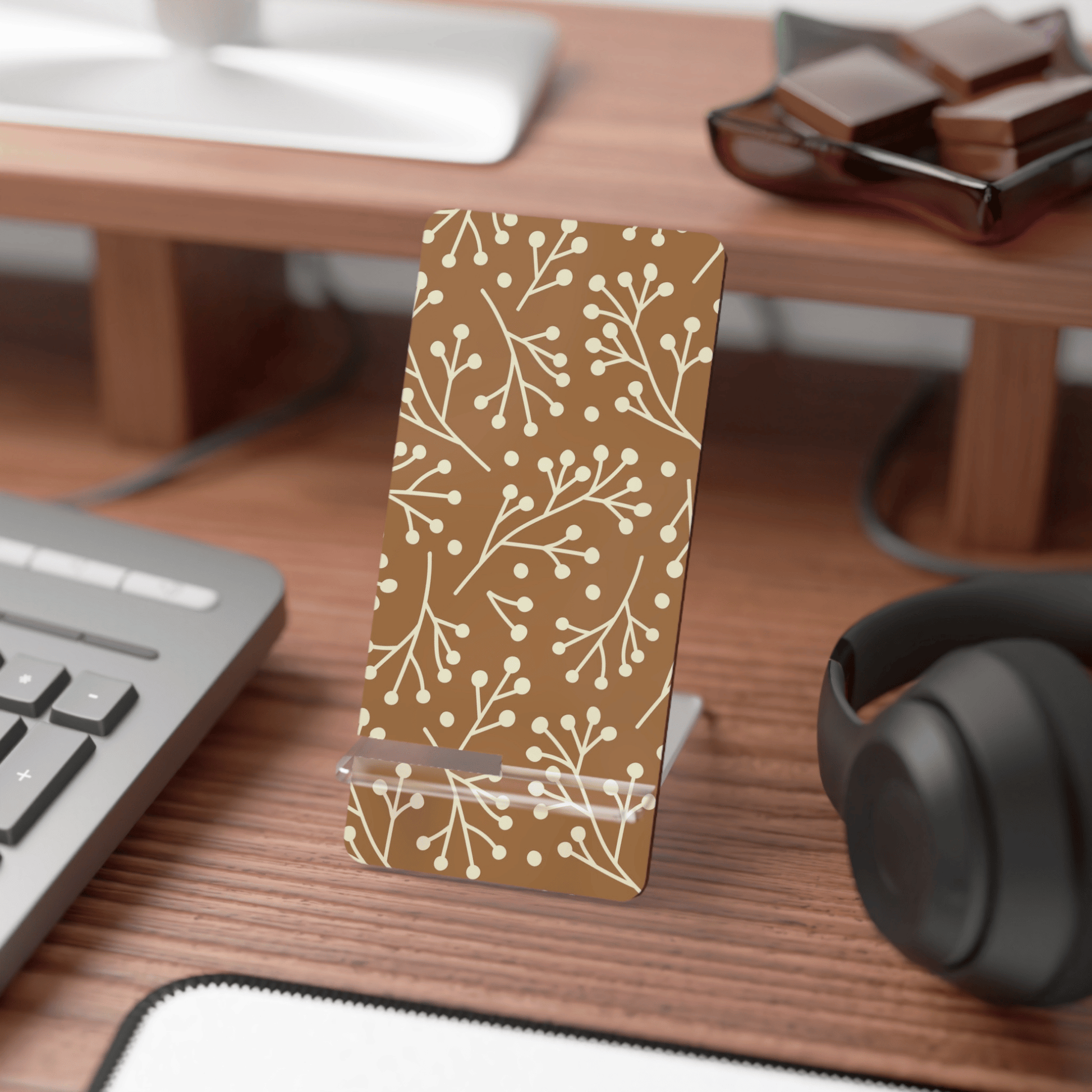 Phone stand with floral pattern on a desk with computer and headphones