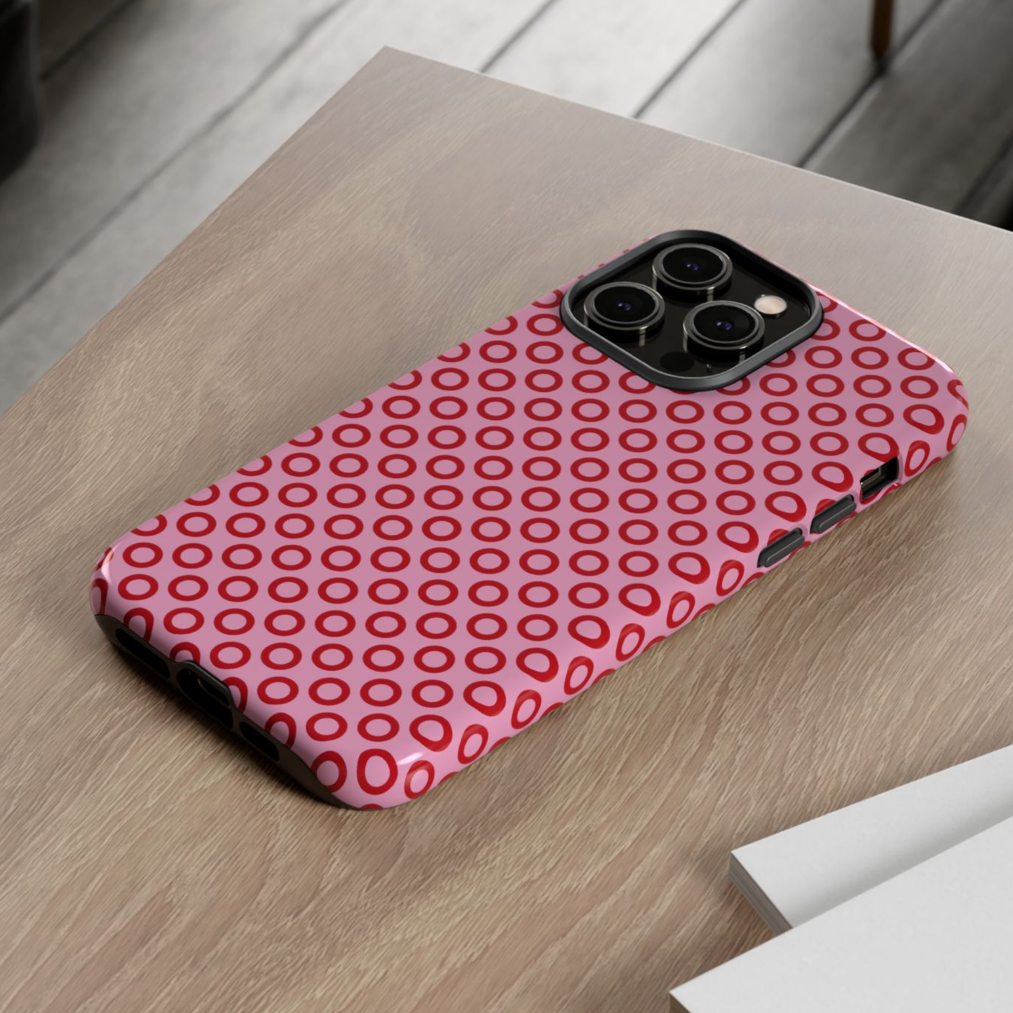 Phone case with red circular pattern on a wooden surface