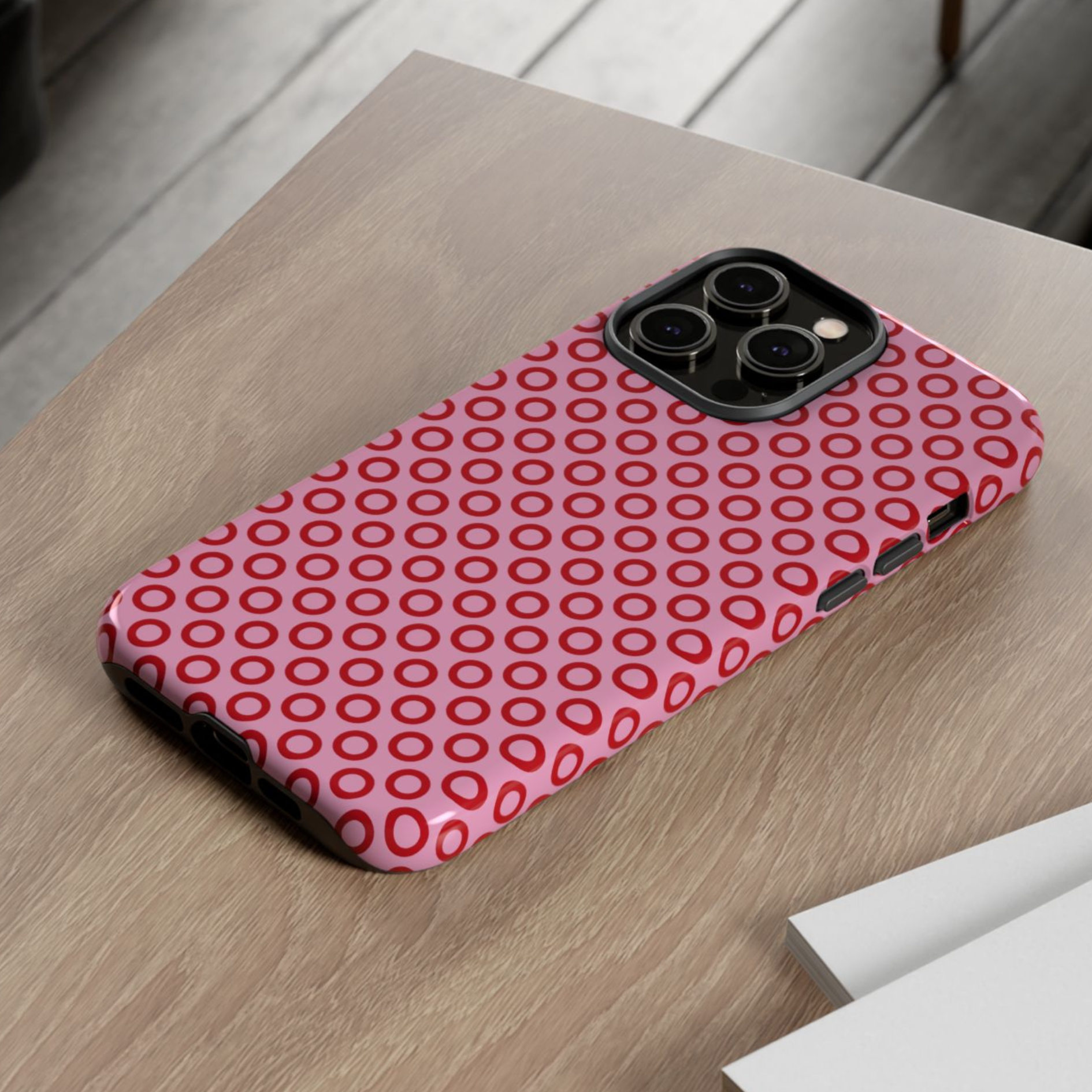 Phone case with red circular pattern on a wooden surface