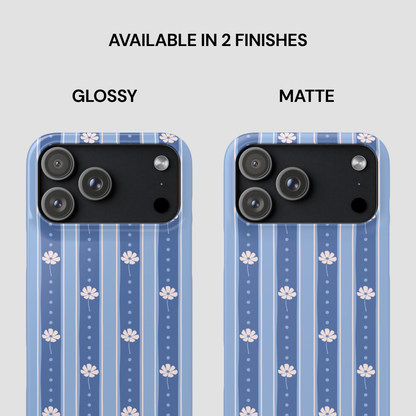Two smartphone cases shown side by side on a light gray background, labeled GLOSSY and MATTE under the text 'AVAILABLE IN 2 FINISHES.' The cases have a blue striped pattern with small white floral motifs and a black camera cutout area.