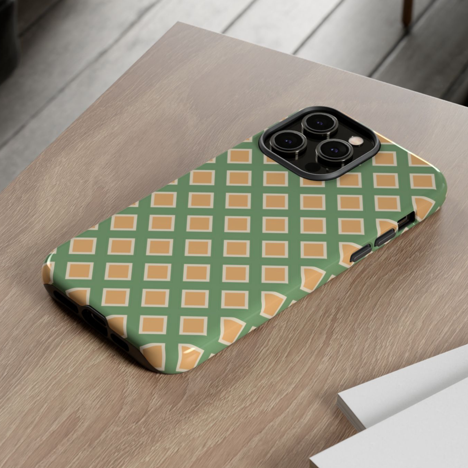 Phone case with green and orange geometric pattern on a wooden surface