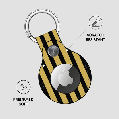Yellow and black striped keychain case with Apple AirTag, featuring 'Scratch Resistant', 'Premium & Soft' text on a light gray background.