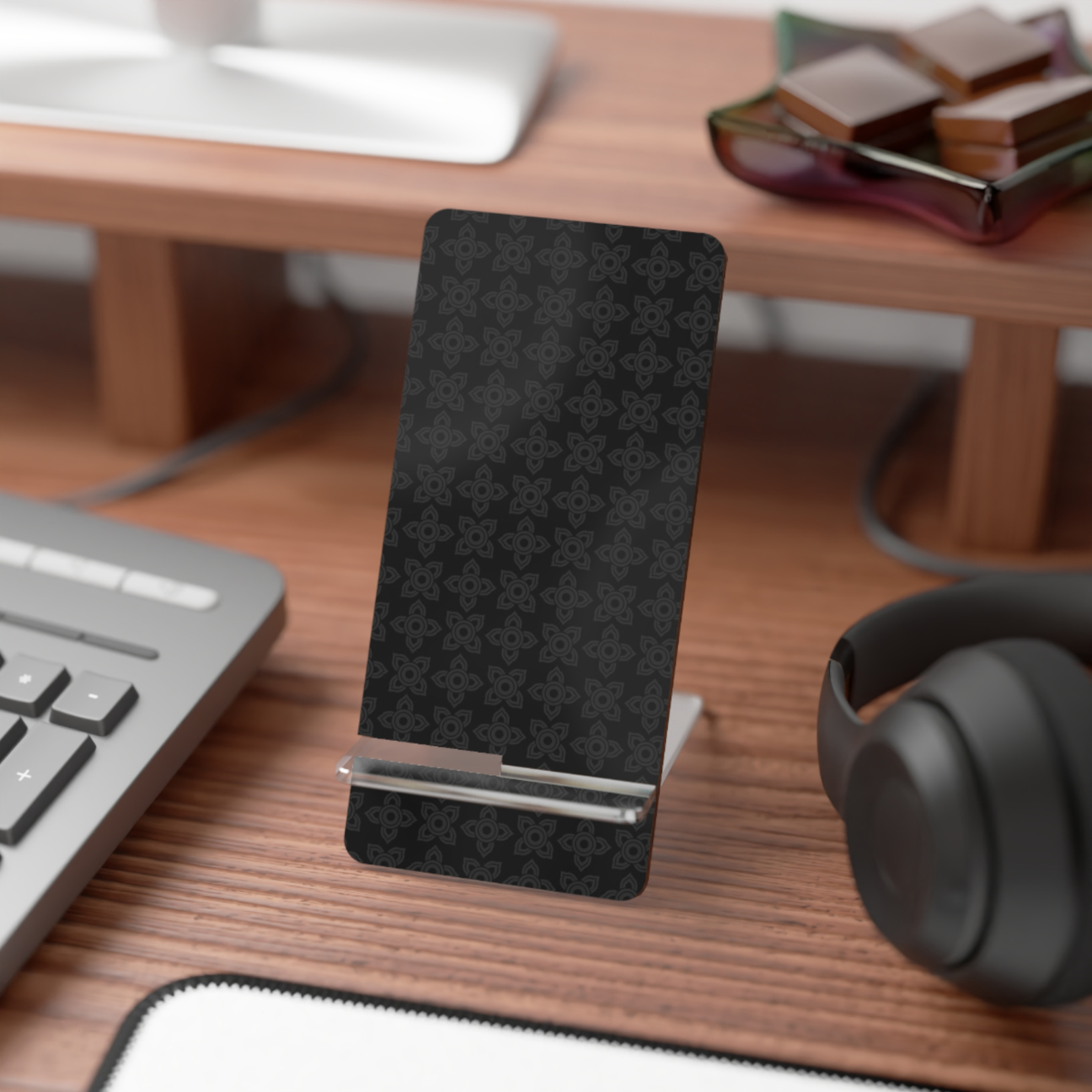 Black phone stand on a desk with a keyboard, mouse, and headphones.