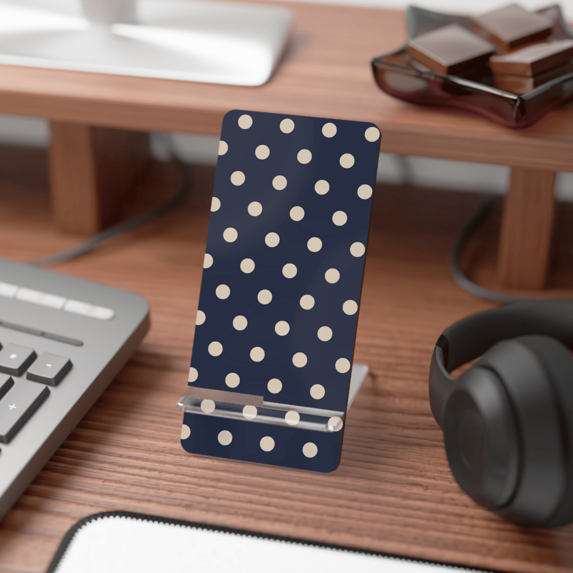 Polka dot phone stand on a desk with keyboard, mouse, and headphones.