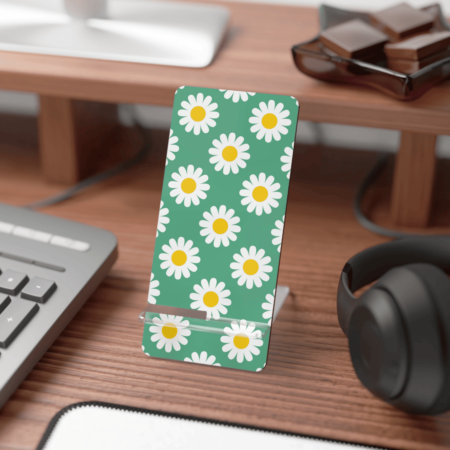 Desk with a phone stand featuring daisy pattern, keyboard, and headphones.