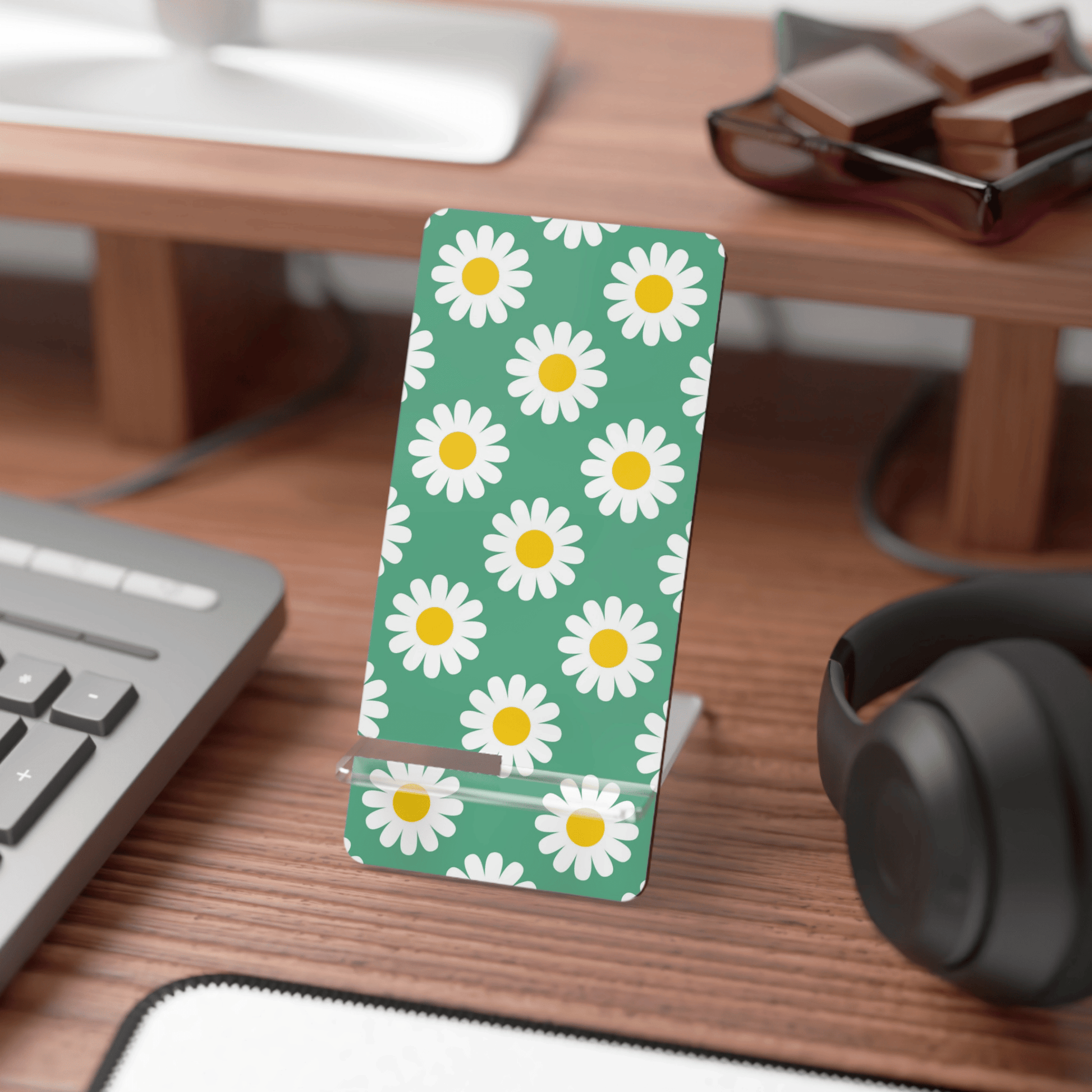 Desk with a phone stand featuring daisy pattern, keyboard, and headphones.