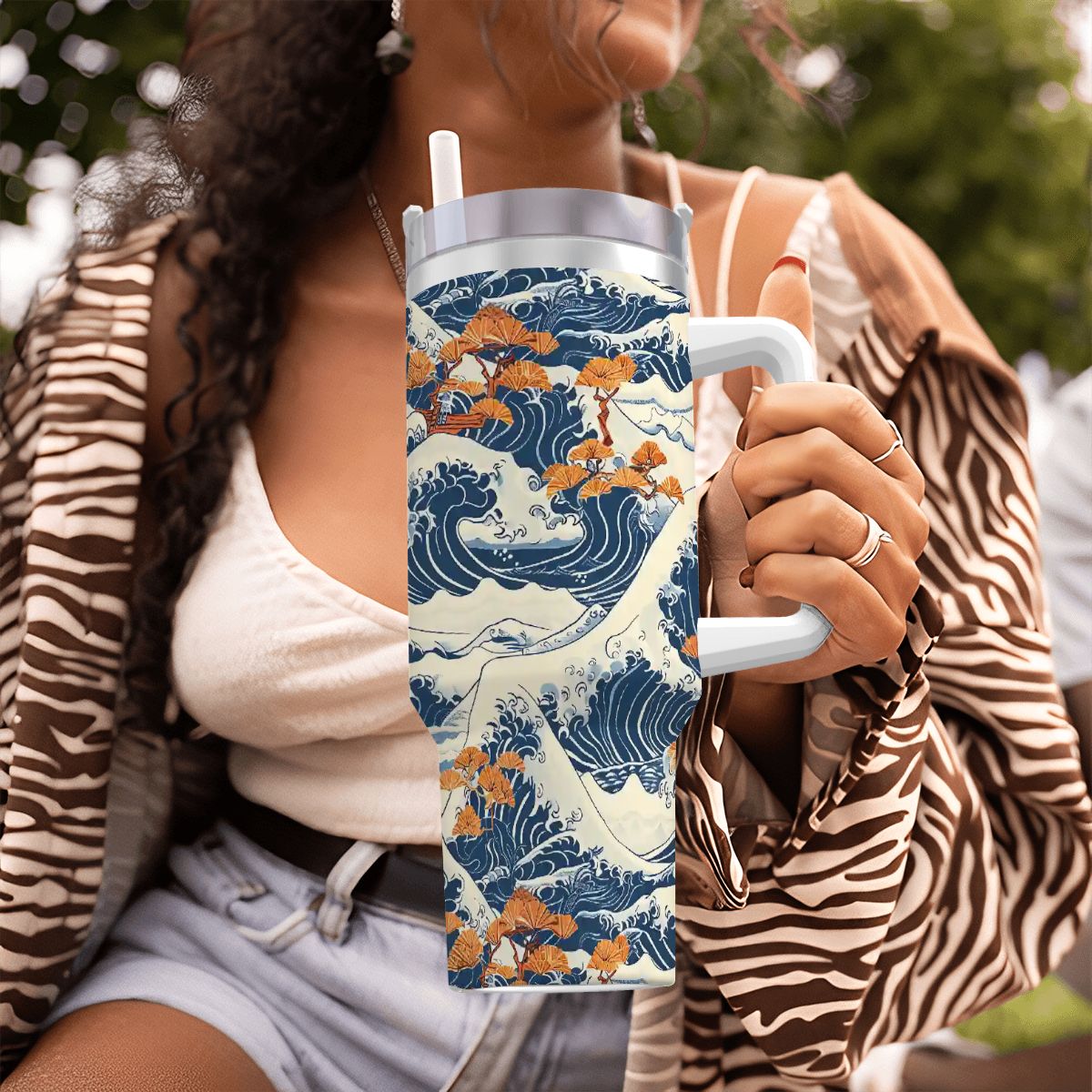Person holding a tumbler with a wave design in an outdoor setting