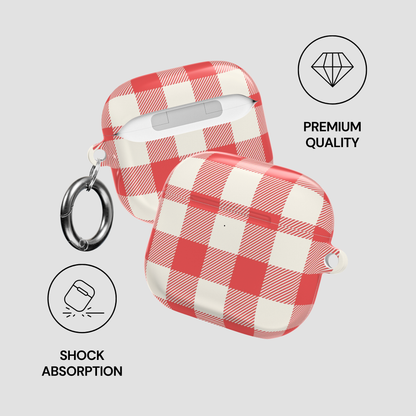 Red and white checkered protective case for wireless earbuds, shown in two views with a metal ring clip on a light gray background. Text and icons highlight premium quality, shock absorption, and earbud compatibility.