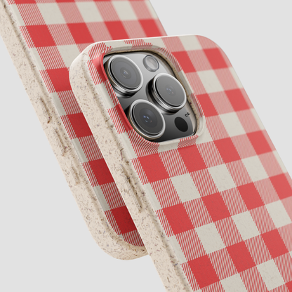 A close-up of a phone case with a red and off-white gingham check pattern and a textured beige edge, shown fitted on a smartphone against a light gray background.