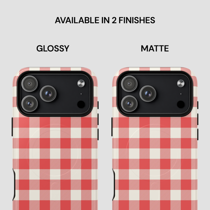 Two smartphone cases shown side by side on a light gray background, labeled GLOSSY and MATTE under the text 'AVAILABLE IN 2 FINISHES.' Both cases have a red-and-cream gingham check pattern and a black camera cutout area.