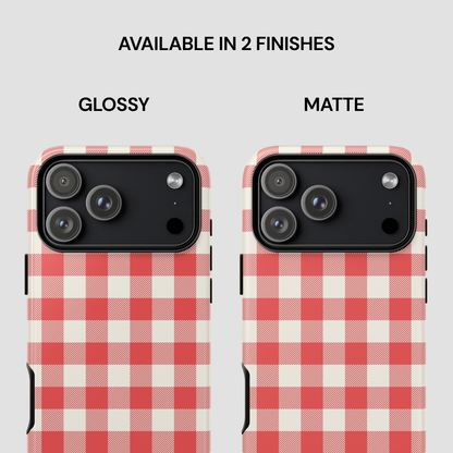 Two phone cases shown side by side on a light gray background, labeled GLOSSY and MATTE under the text 'AVAILABLE IN 2 FINISHES.' Both cases have a red and off-white gingham check pattern and are shown fitted on phones with black camera cutouts.