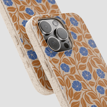 A close-up of a phone case with a beige background, brown leaf pattern, and blue flower motifs, shown overlapping another case on a light gray background.