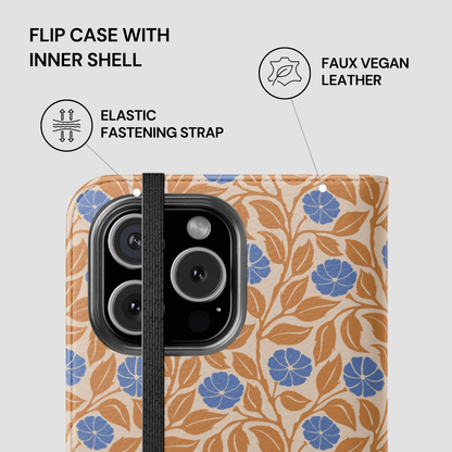 A phone case with a beige background, blue flowers, and orange-brown leaves, featuring a black elastic strap and a black camera cutout. The image includes text and icons explaining features like the flip case with inner shell, elastic fastening strap, and faux vegan leather.