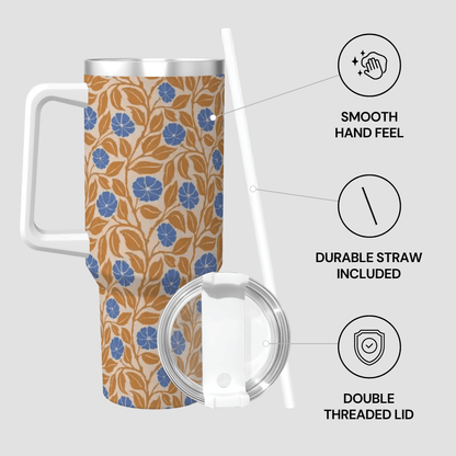 A patterned insulated travel mug with a floral print on a light background, shown with a white handle, clear lid, and straw on a light gray background with feature callouts.