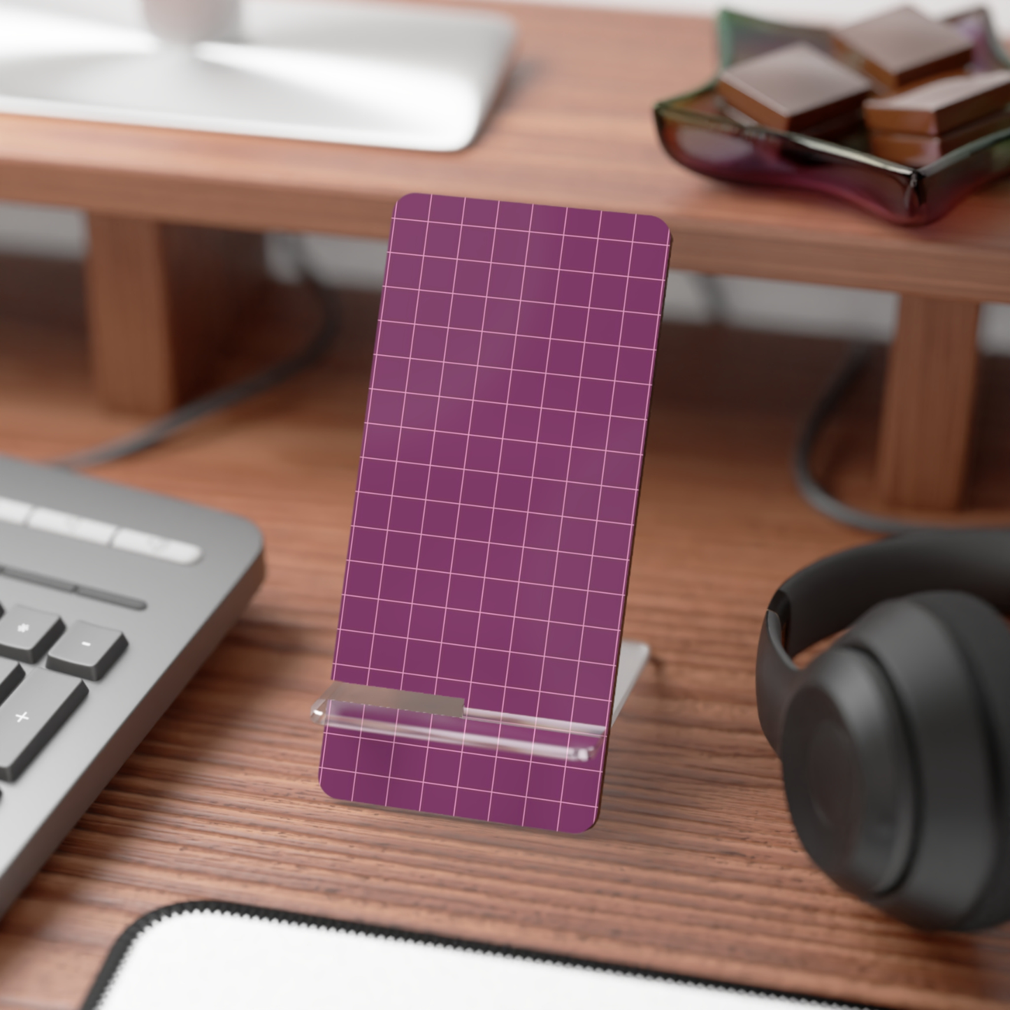Purple grid phone stand on a desk with keyboard, mouse, and headphones.