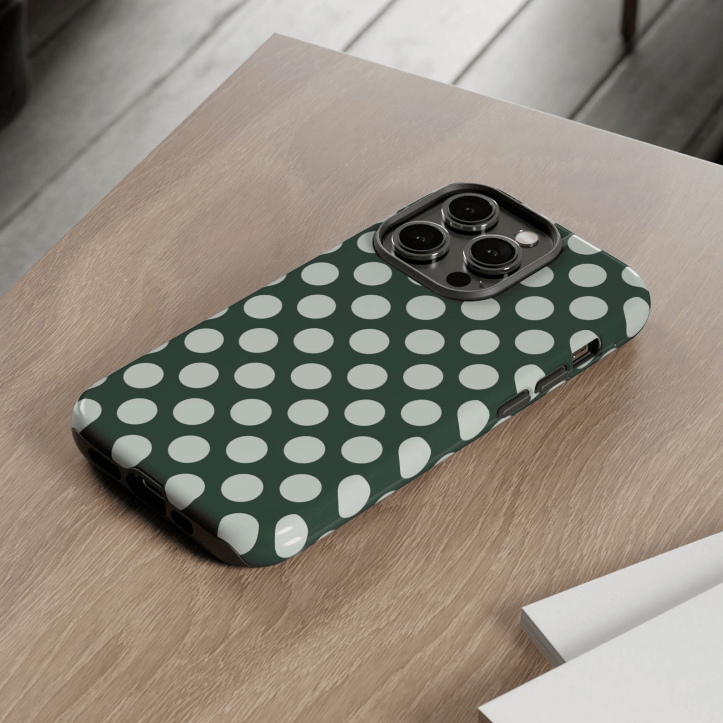 Phone case with green and white polka dot pattern on a wooden surface