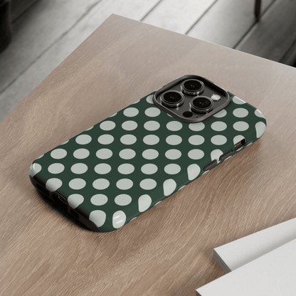Phone case with green and white polka dot pattern on a wooden surface