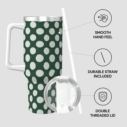 Green polka dot travel mug with a lid and straw on a light gray background