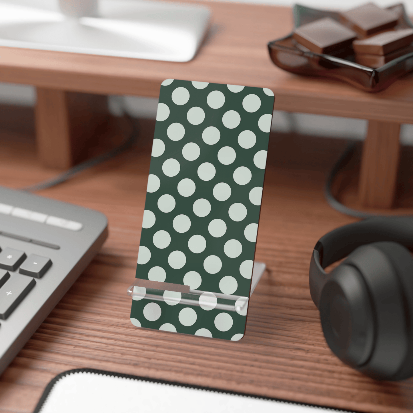 Polka dot phone stand on a desk with keyboard, mouse, and headphones.