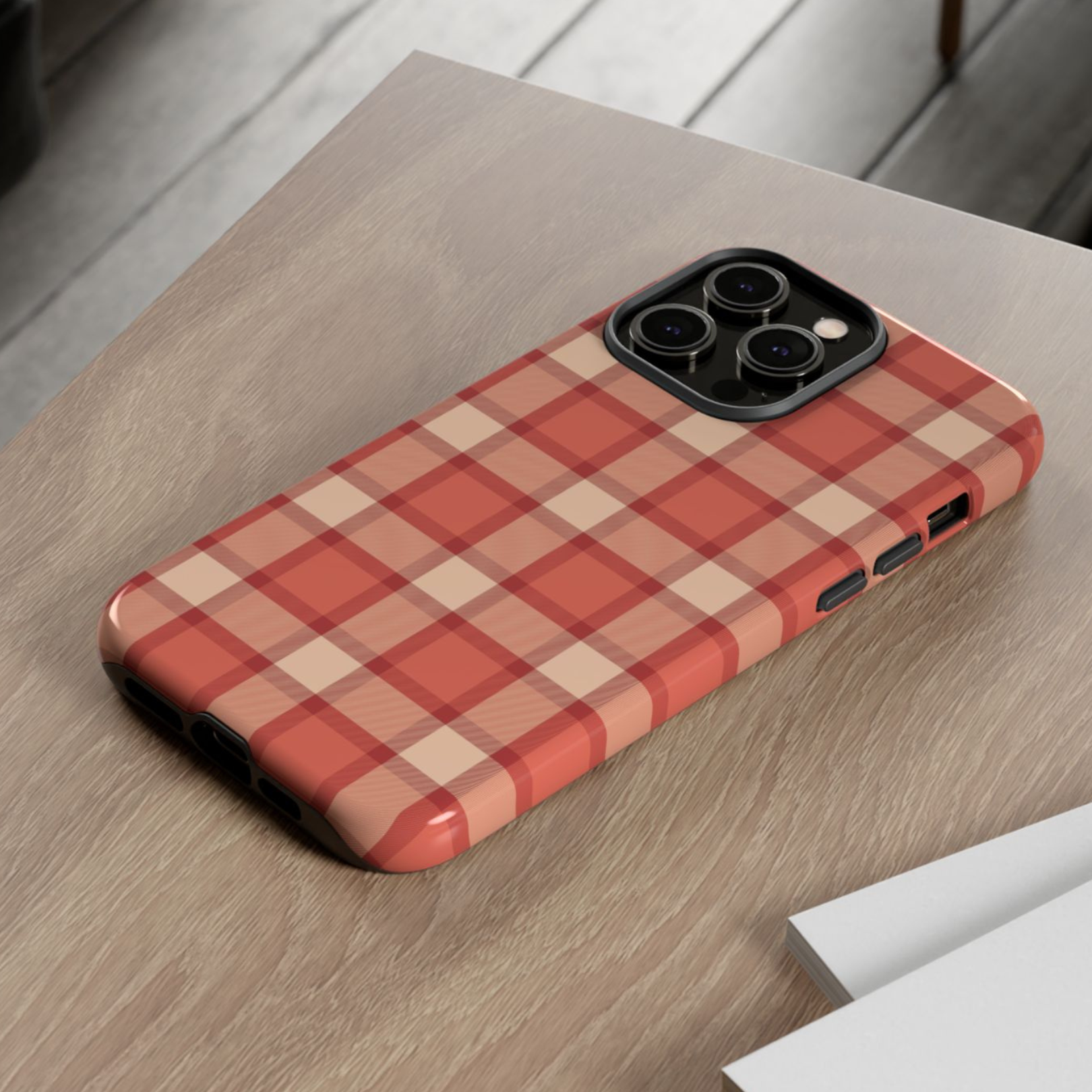 Phone case with red and beige checkered pattern on a wooden surface