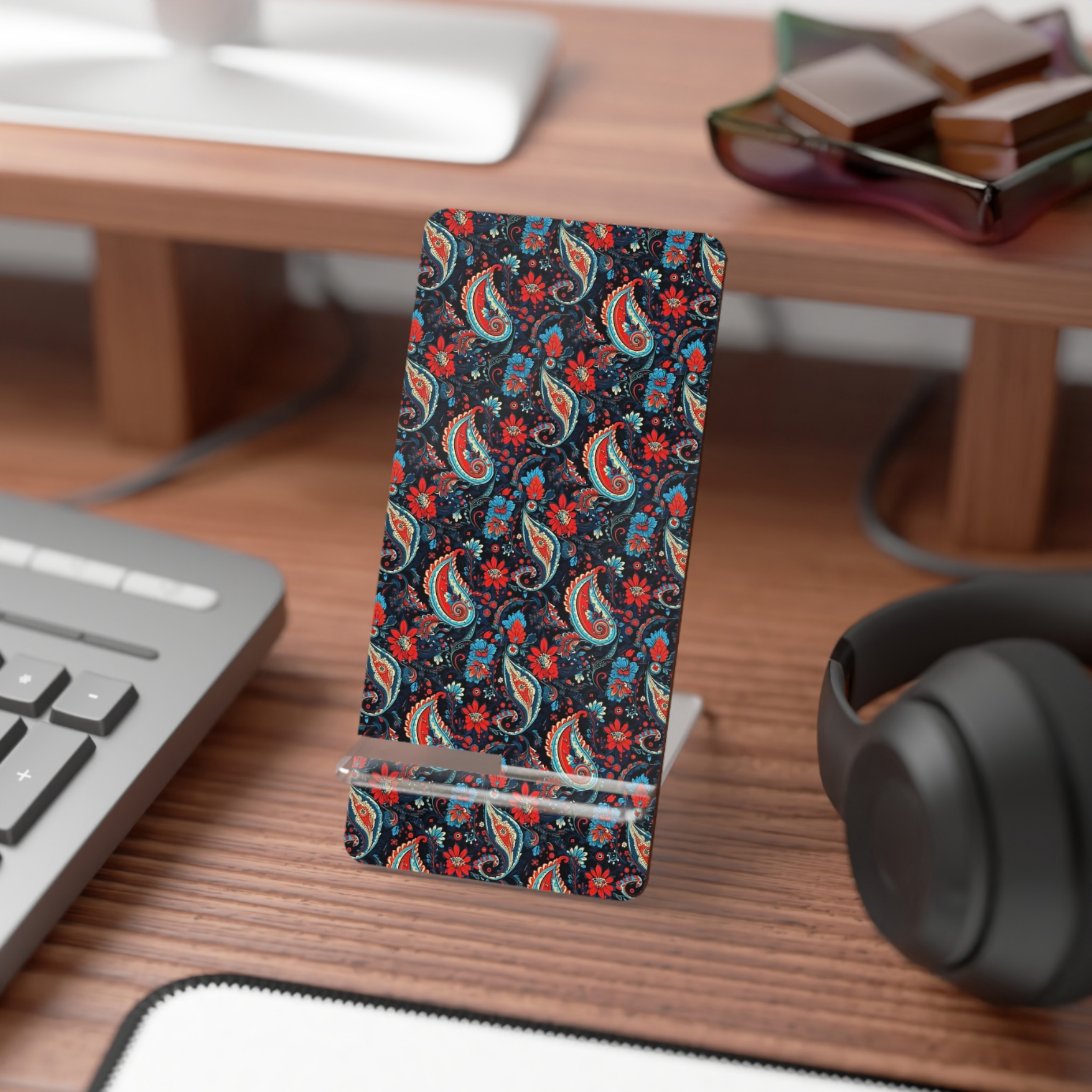 Phone case with colorful paisley pattern on a desk with keyboard and headphones