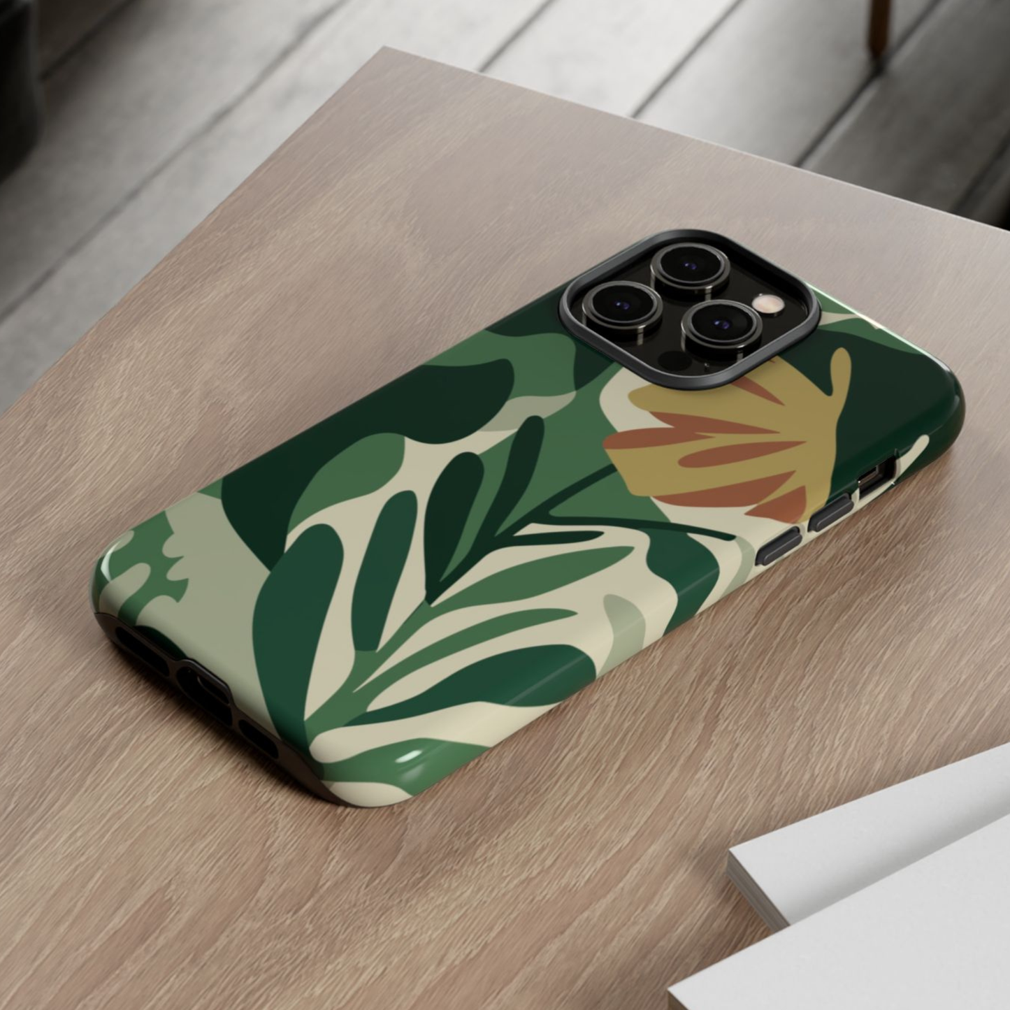 Phone case with green leaf pattern on a wooden surface