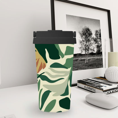 Tumbler with green leaf pattern on a desk with books and a framed picture in the background