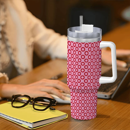 Pink patterned mug with handle on a desk next to glasses and a notebook