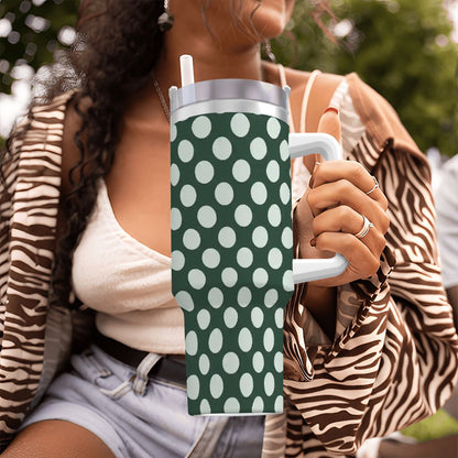 Person holding a green tumbler with white polka dots outdoors