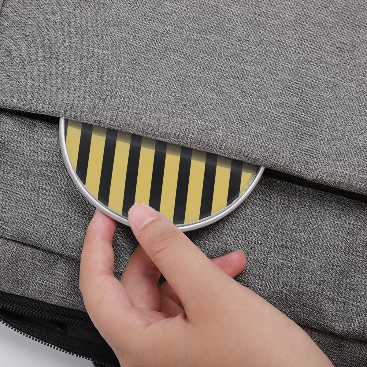 Hand pressing a striped circular object on a gray textured surface