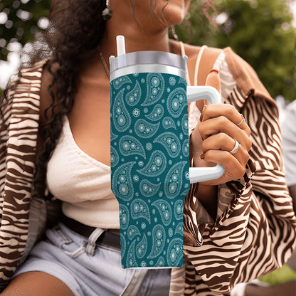 Person holding a teal tumbler with white paisley pattern outdoors
