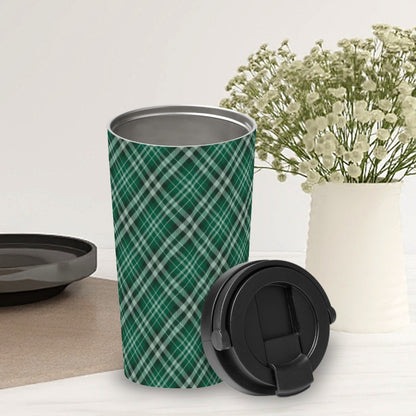 Green plaid travel mug with black lid on a white surface with a vase of flowers in the background.