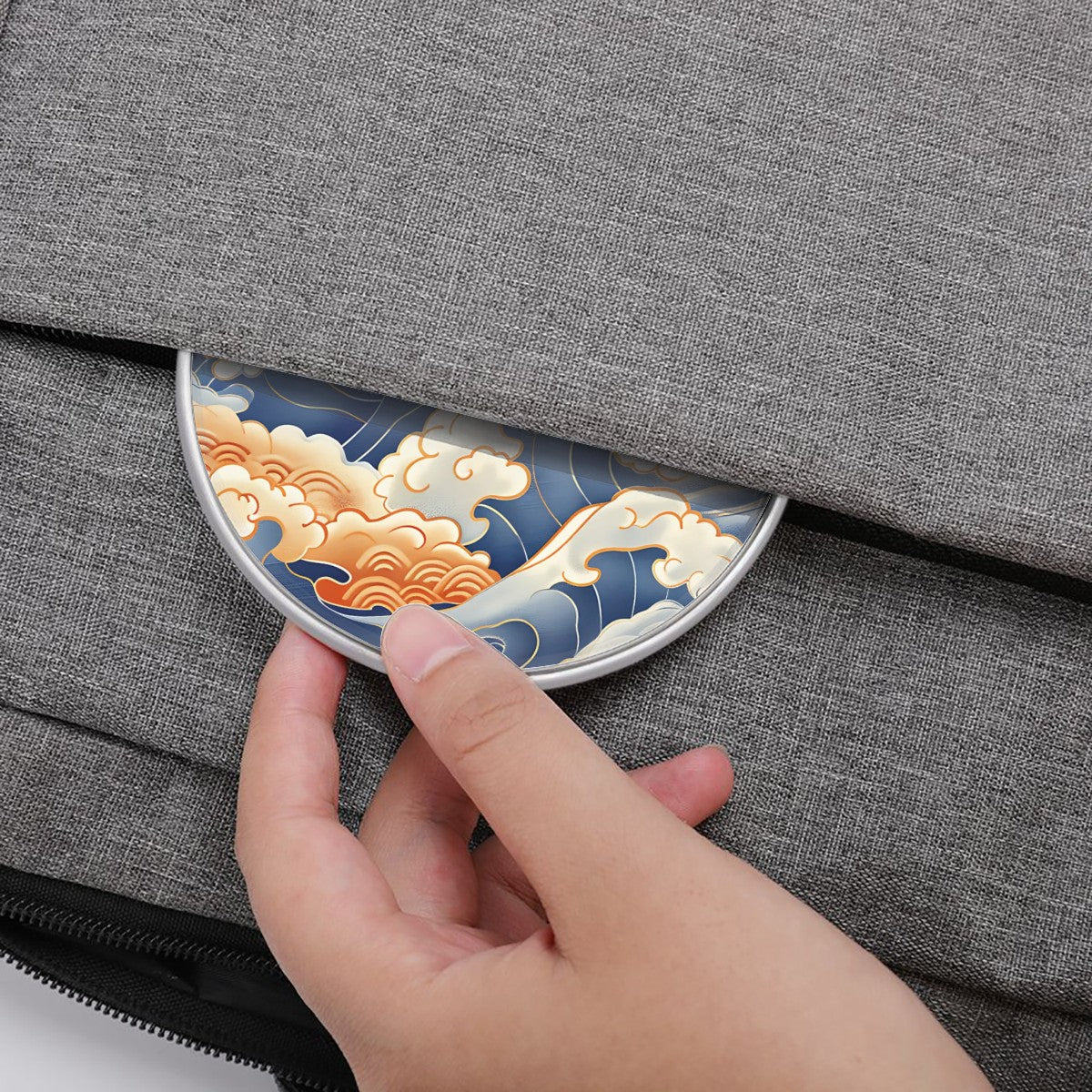 Hand placing a decorative wireless charger with wave design on a gray fabric surface