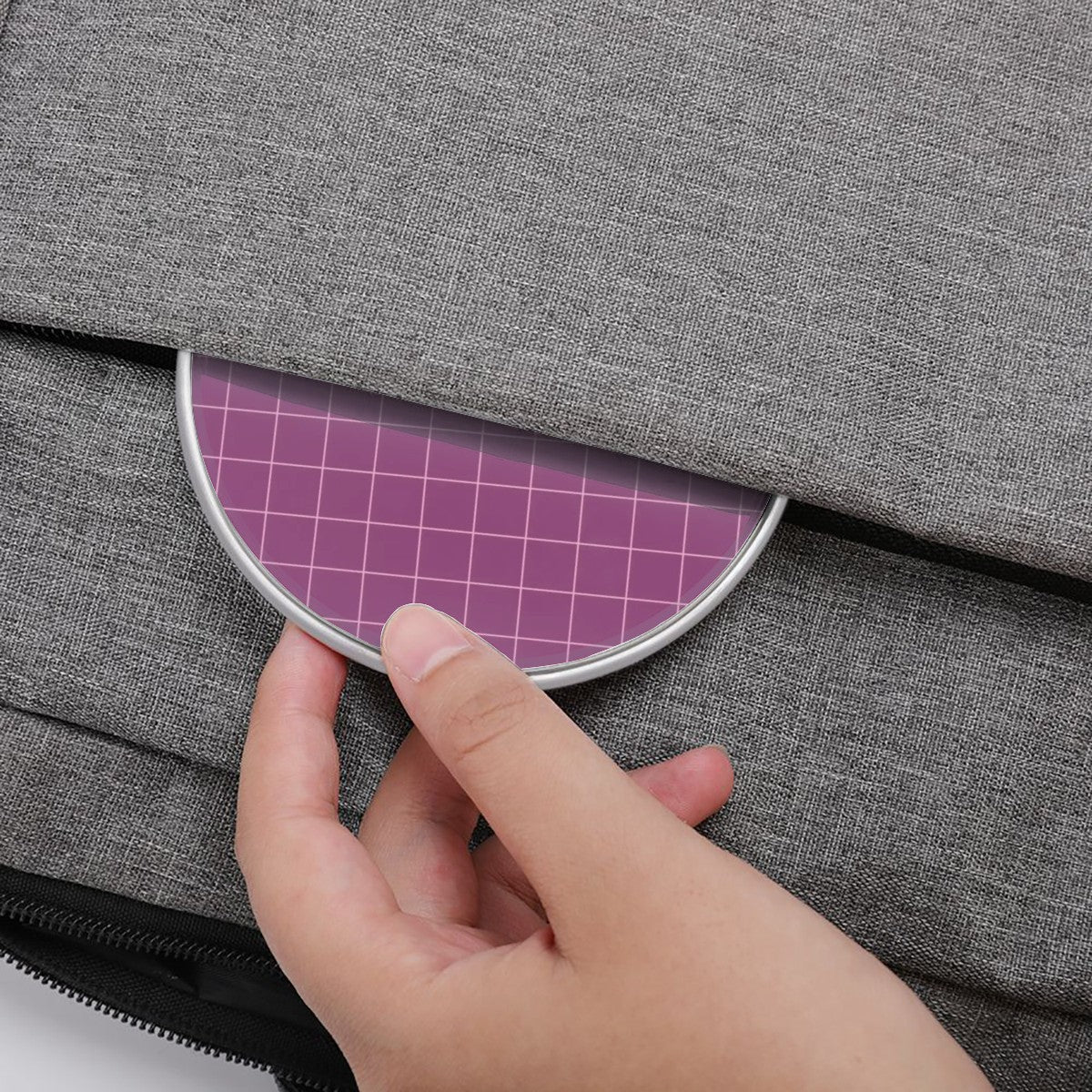 Hand opening a gray fabric bag with a pink plaid lining