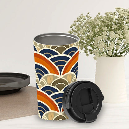 Travel mug with geometric pattern on a white surface with a vase of flowers in the background