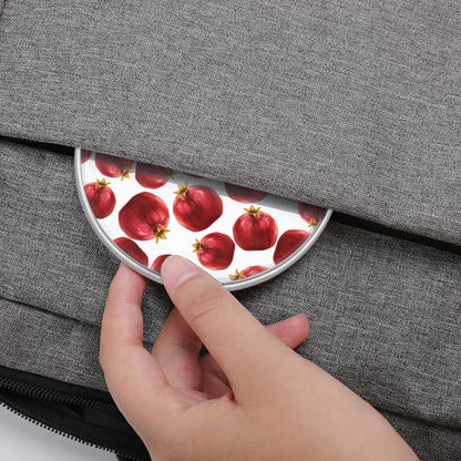 Hand placing a round coaster with pomegranate design onto a gray textured surface.