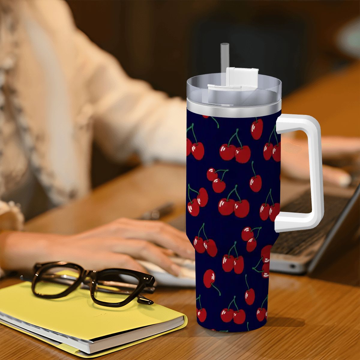 Tumbler with cherry pattern on a desk next to glasses and a notebook