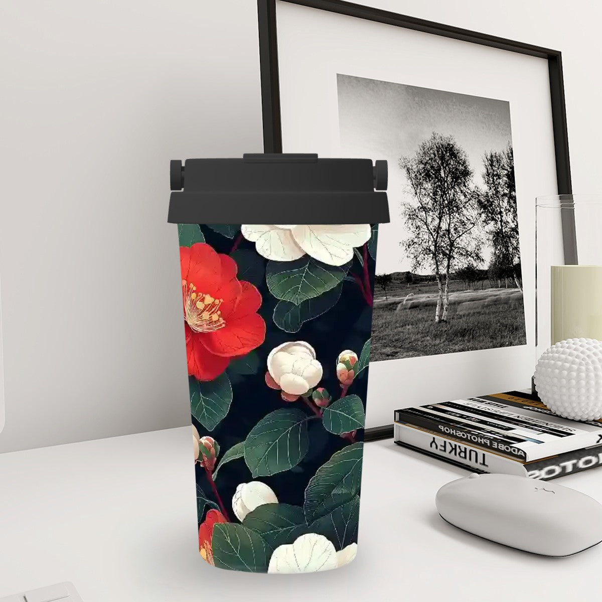 Tumbler with floral design on a desk next to a framed black and white photo