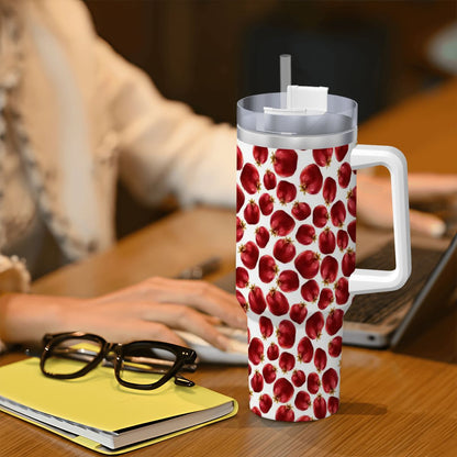 Tumbler with red berry pattern on a desk with a person using a laptop in the background