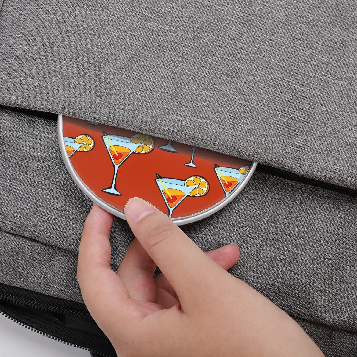 Coaster with cocktail design being placed into a gray bag