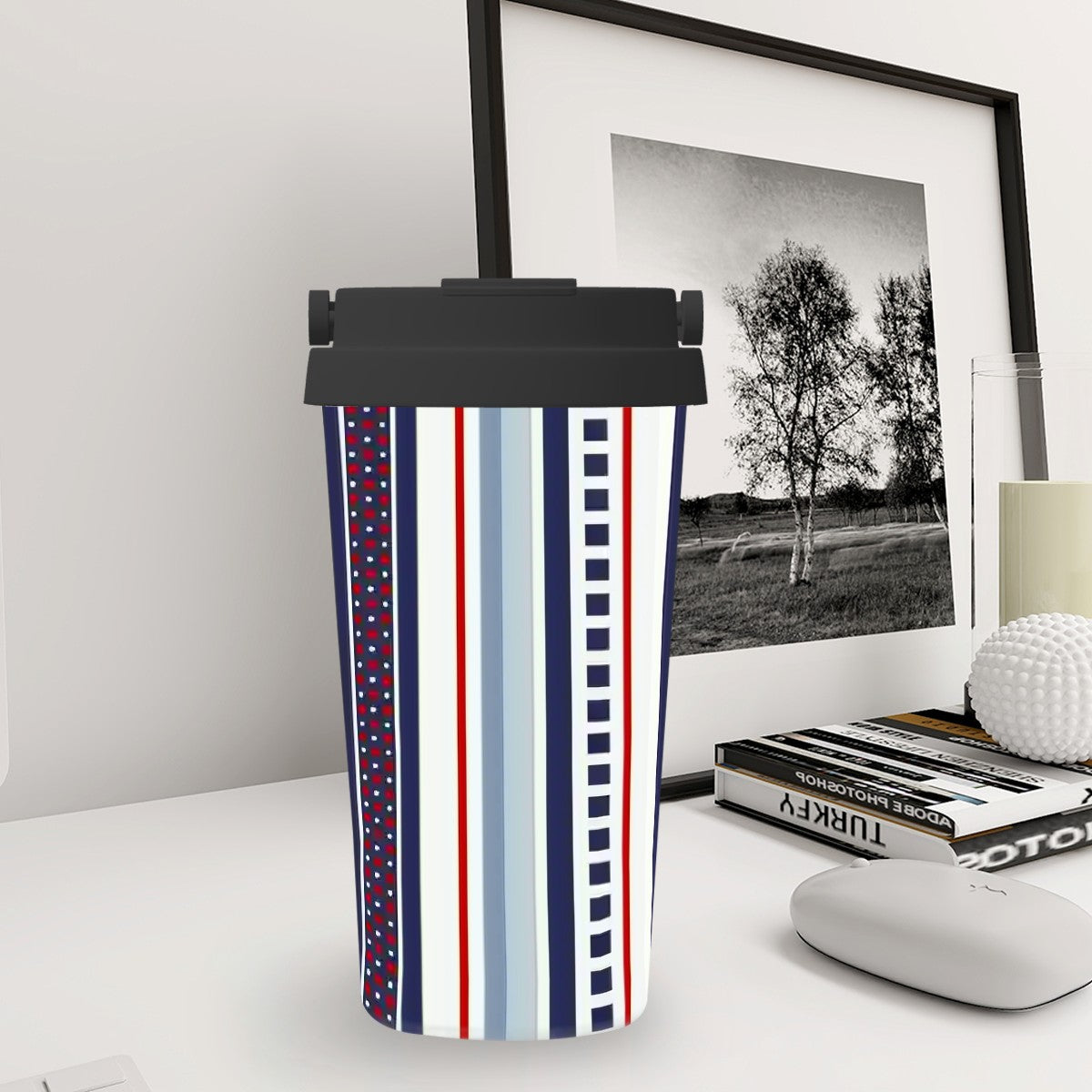 Tumbler with striped design on a desk next to a framed picture and books